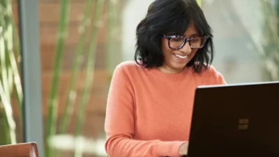 En person som bär en orange tröja och använder en bärbar dator.