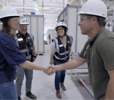 A group of people wearing hard hats shaking hands.