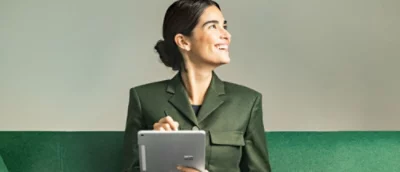 A woman in green blazer holding a tablet.