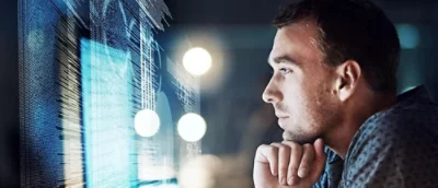 Person framför en datorskärm som visar kod.