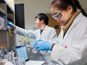 A person wearing glasses and a white lab coat