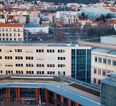 Budynek z wieloma oknami i logo firmy Michelin, otoczony pokrytym śniegiem terenem i drzewami.