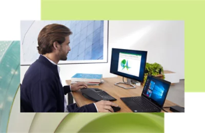 Laki-laki bekerja di desktop dan laptop di meja kantor modern, menganalisis data di layar dengan bagan grafis.