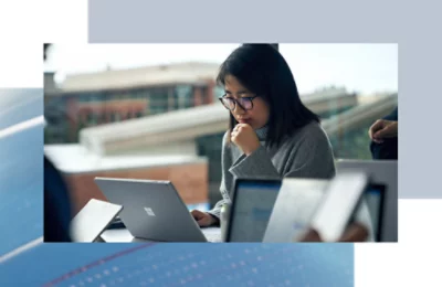 Persona seduta a un tavolo, concentrata a lavorare su un portatile in un'area di lavoro condivisa.