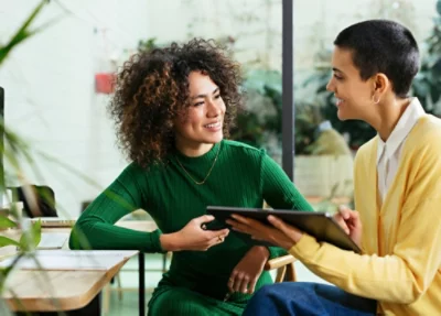 En grönklädd leende person håller i en surfplatta