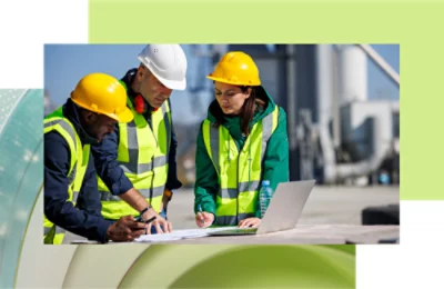 En grupp personer med säkerhetsvästar och skyddshjälmar som tittar på en dator