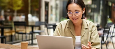 En kvinna ler mot en bärbar dator.