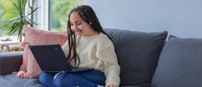 Una persona sentada en un sofá con un equipo.