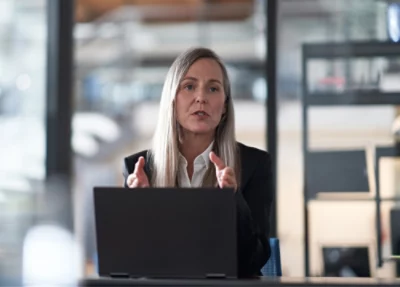 En kvinna sitter vid ett bord med en bärbar dator.