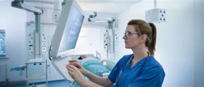 A woman in blue scrubs using a computer.