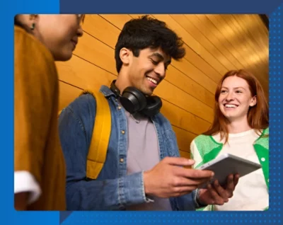 En man och ett barn arbetar tillsammans på en bärbar dator vid ett bord i ett klassrum. Barnet ler.