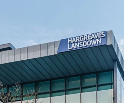 Das Zeichen „Hargreaves Lansdown“ auf einem modernen Gebäude mit klarem Himmel im Hintergrund.