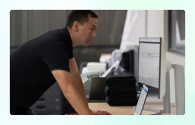 Standing person reviewing desktop monitors