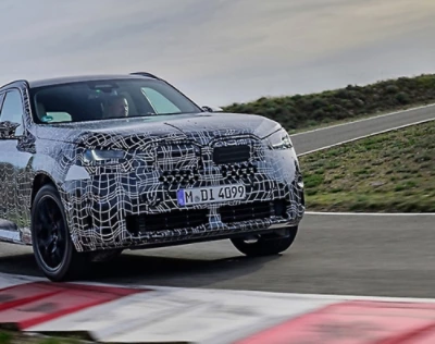 Ein gelber Volkswagen-Bus, der bei Sonnenuntergang an einer Küstenstraße geparkt ist, mit drei Personen, die im Hintergrund sitzen und sich unterhalten.
