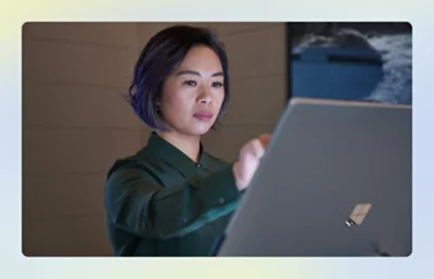 Person using a large laptop in a dimly lit workspace.