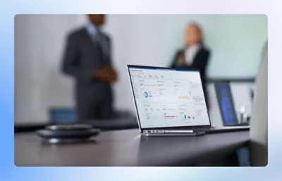 A laptop on a table with people blurred in the background.