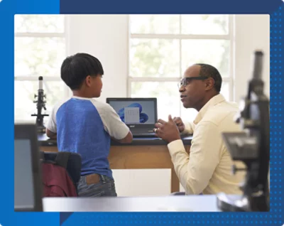 A woman wearing a mask looking at a laptop with a girl wearing a striped fabric mask nearby.