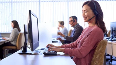 En person iförd headset skriver på ett tangentbord vid ett skrivbord.