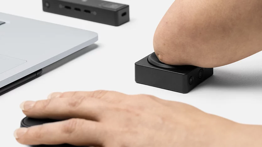 A person who has a physical disability pushes a Microsoft Adaptive Button.