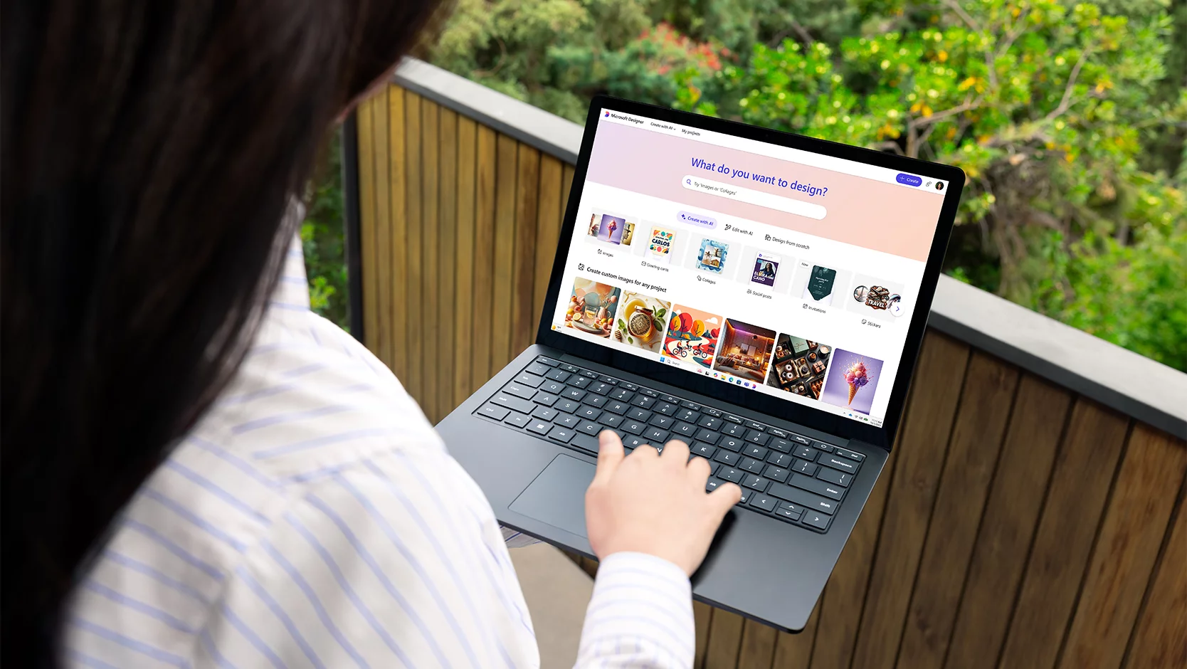 Uma pessoa usa o Microsoft Designer em um laptop enquanto está ao ar livre.