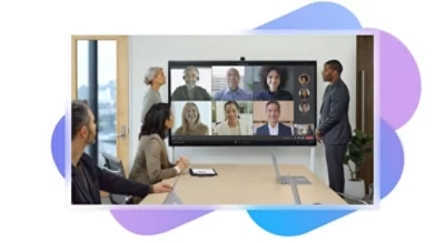 Un grupo de personas en una sala de reuniones participa en una llamada de Teams en la televisión montada en la pared que tienen detrás.