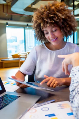 En kvinna på ett kontor som arbetar på sin surfplatta och pratar