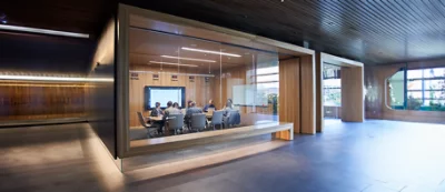 Um homem de bata azul está em frente a um portátil, com paredes verticais às riscas azuis e brancas como fundo.