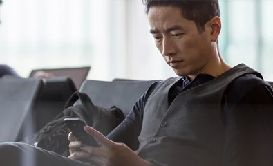 Um homem sentado e a olhar para o seu tablet.