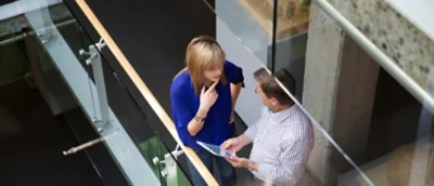 A man and woman discussing something while the man is holding tablet