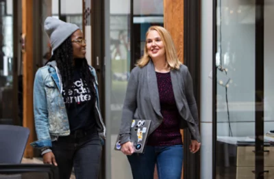 Duas pessoas à conversa enquanto atravessam um corredor.